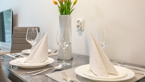 A dining table set with white plates, napkins, and wine glasses, accompanied by a vase of yellow tulips. - Vacation apartment by the sea, vacation on the island of Usedom, Apartment MATEJKI 4 (Swinoujscie)