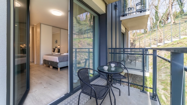 A modern balcony with a glass door leading to a bedroom, a small table with chairs, and a view of a hillside. - Vacation apartment by the sea, vacation on the island of Usedom, Apartment MATEJKI 4 (Swinoujscie)