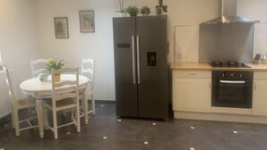Cocina compacta con refrigerador, horno y un tragaluz sobre la mesa de comedor.