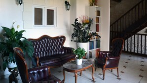 Una sala de estar con un sofá de cuero, dos sillones, una mesa de centro y una estantería.