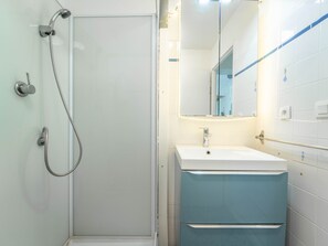 A bathroom with a glass shower enclosure, a white sink, and a mirror with LED lights.