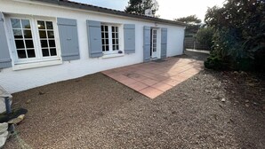 Une maison avec une allée en gravier et un petit espace patio.
