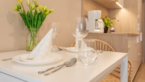 Een eettafel gedekt met borden, bestek en een vaas tulpen.