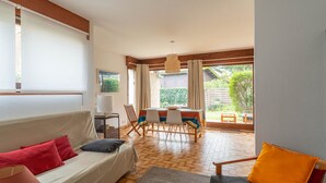 Una habitación acogedora con sofá, sillón, mesa de comedor y vistas al jardín.