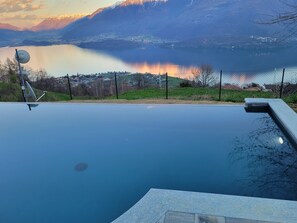 An infinity pool with a view of a lake and mountains.