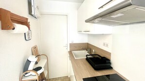 Une cuisine de taille réduite, équipée d’un évier, d’une cuisinière et d’un petit plan de travail.