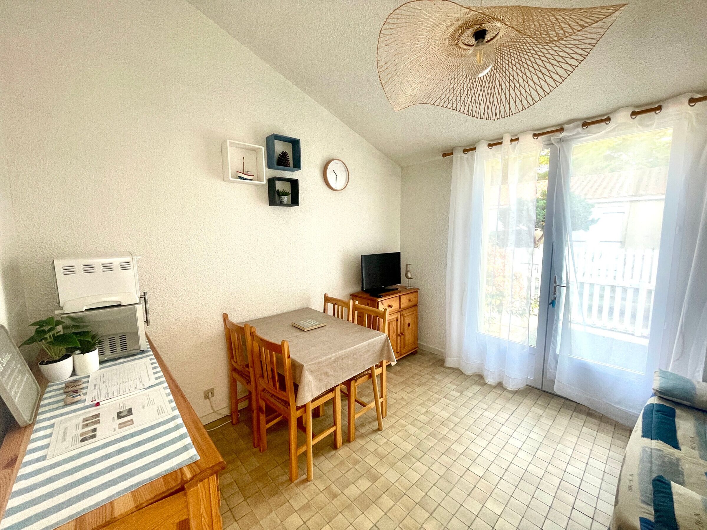 A compact living space with a dining area, a television, and a ceiling fan.
