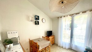 Un espace de vie compact comprenant un coin repas, un téléviseur et un ventilateur de plafond.