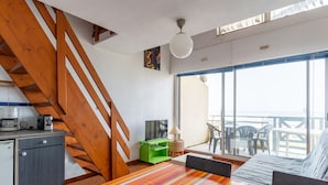A room with a bed, a desk, a kitchenette, a staircase, and a balcony with a view of the sea. - Apartment with ocean view, balcony, and all comforts, in Mimizan for 6 people (Mimizan)
