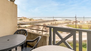 A balcony with a view of the beach, a table, and chairs. - Apartment with ocean view, balcony, and all comforts, in Mimizan for 6 people (Mimizan)