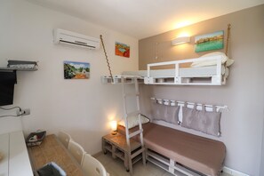 Une chambre avec un lit superposé, un bureau, une chaise et des œuvres d’art accrochées aux murs.