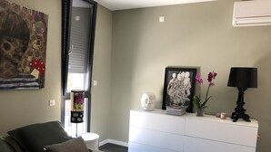 Een slaapkamer met een bed, een dressoir, een raam met zonwering en een schilderij aan de muur.