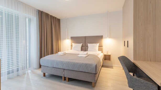 Un dormitorio moderno con una cama grande, mesitas de noche, un escritorio y una silla.