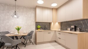 Eine moderne Küche mit Marmorarbeitsplatte, Holzschränken und einem Essbereich mit grauen Stühlen.