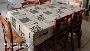 A dining area with a table set for four, a television in the background, and a clock on the wall. - Vacation home close to the beach (La Faute-sur-Mer)