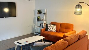 En moderne stue med en sofa, et sofabord, et fjernsyn og en reol.