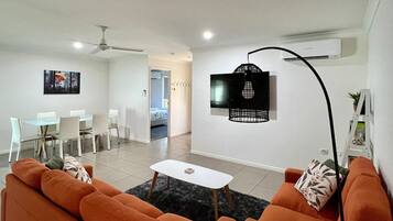 A modern living room with orange sofas, a white coffee table, and a black floor lamp.