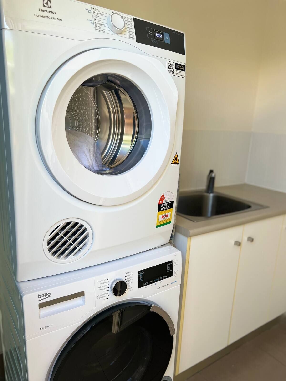 A front-loading washing machine with a control panel, stacked on top of a dryer.