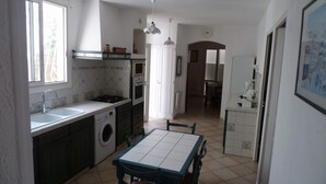 Une cuisine de taille réduite équipée d’un lave-linge, d’une table à manger et d’un réfrigérateur.