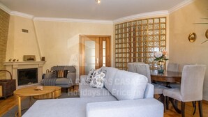 Un salon avec une cheminée, un canapé, une table à manger avec des chaises et une cloison décorative en verre.