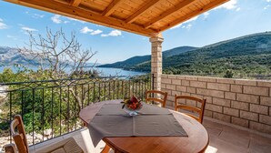 A wooden table with a glass bowl of fruit on a balcony overlooking a scenic view of a lake and mountains. - 1 bedroom stunning apartment in Kneze (Kneze)