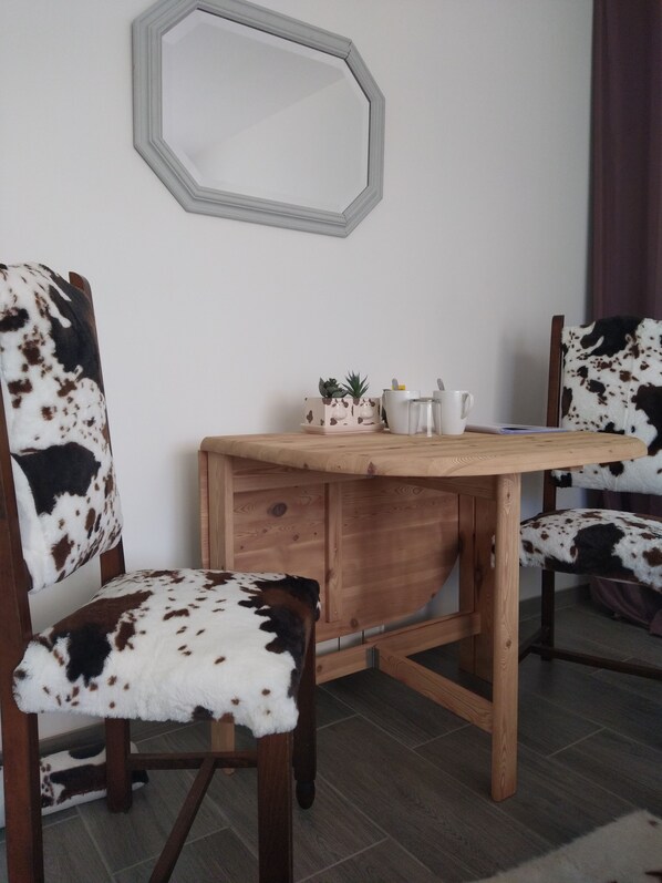 Un comedor con una mesa de madera y sillas con tapicería de cuero de vaca. Hay una pequeña planta en maceta y una taza blanca sobre la mesa.
