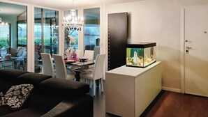 Ein modernes Wohnzimmer mit Essbereich, einer Kronleuchter, einem großen Aquarium und einer Tür.
