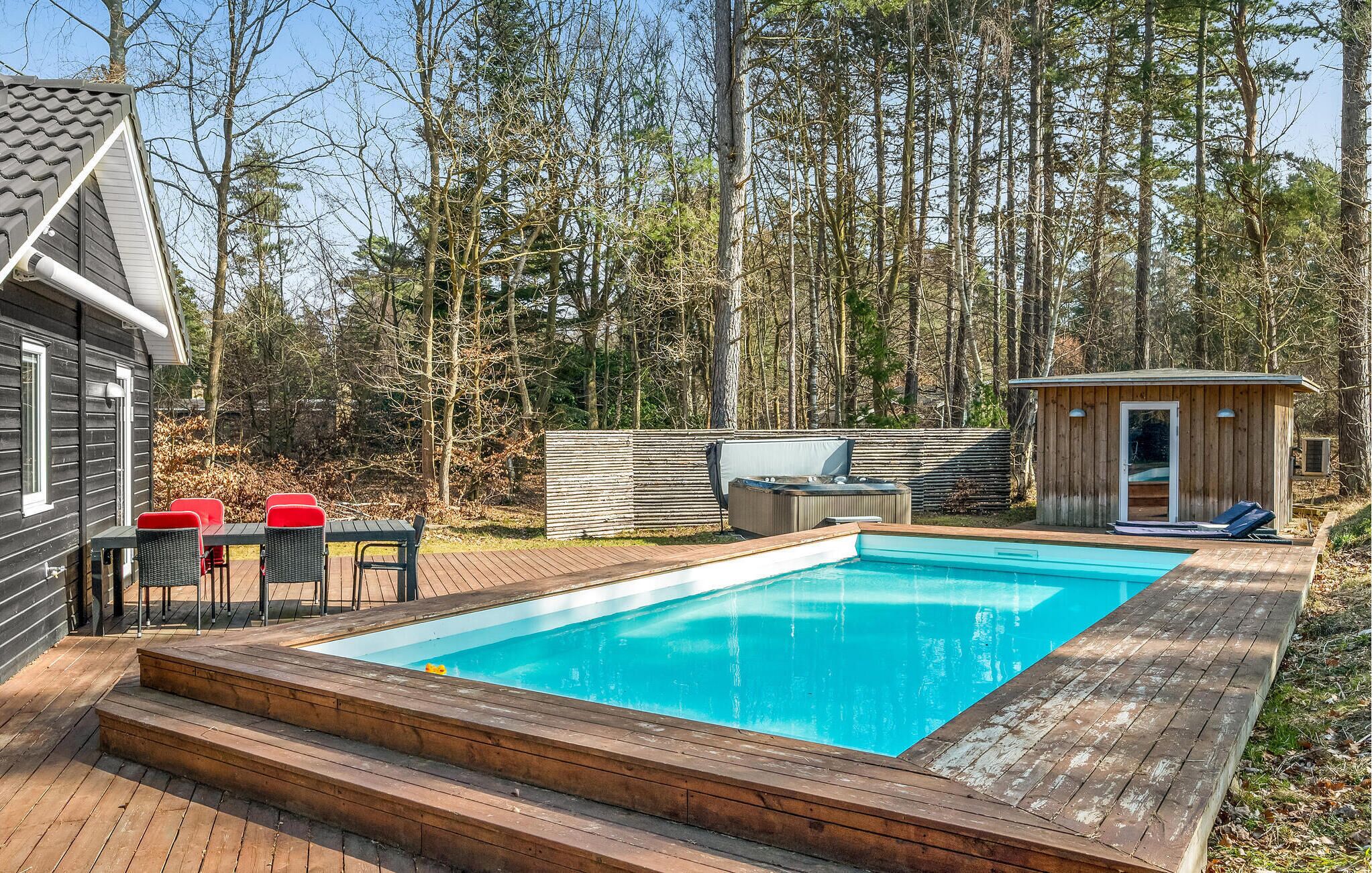 A swimming pool with wooden decking, a hot tub, and outdoor seating.