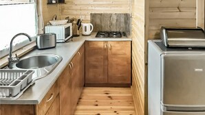 Une cuisine compacte équipée d’un évier, d’un four à micro-ondes, d’une bouilloire, d’une cuisinière et d’un petit réfrigérateur.