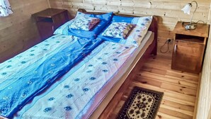 Une pièce en bois avec un lit, une table de chevet, une lampe et un tapis à motifs.
