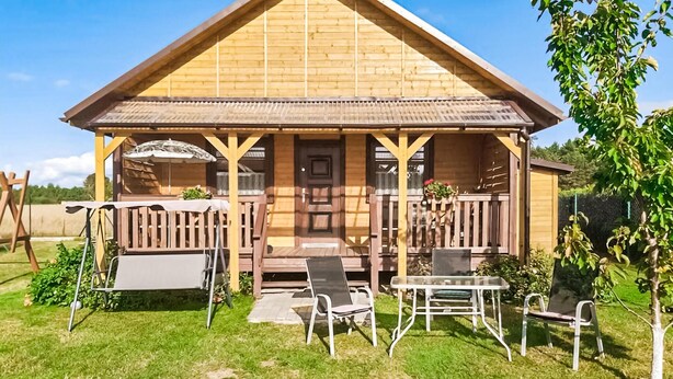 Une cabane en bois avec une véranda, des sièges d’extérieur et une petite table.
