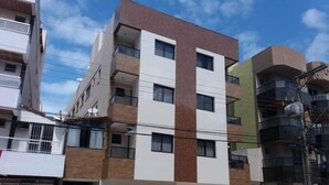 Ein mehrstöckiges Wohngebäude mit moderner Gestaltung, das Ziegel- und weiße Fassaden, Balkone und einen verschlossenen Eingang kombiniert.