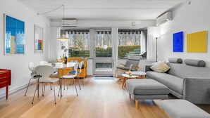 A modern living room with a grey sofa, a dining table with yellow chairs, and a red cabinet.