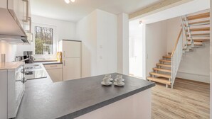 A modern kitchen with a central island, built-in appliances, and a wooden staircase. - Cozy home in Süssau/Ostsee with sauna (Süssau/Ostsee)