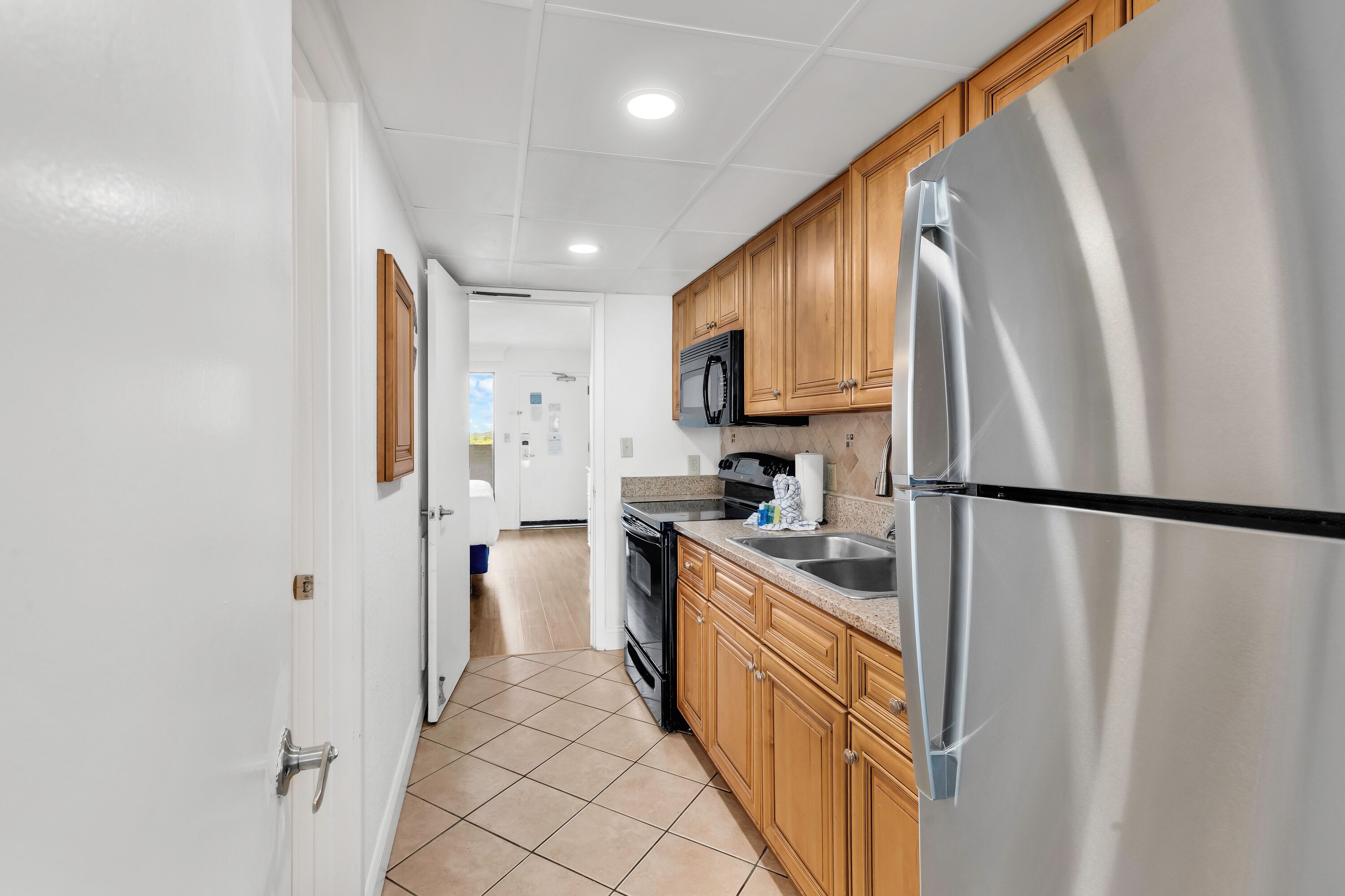 A kitchen with wooden cabinets, a stainless steel refrigerator, a microwave, and a stove.