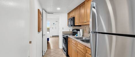 A kitchen with wooden cabinets, a stainless steel refrigerator, a microwave, and a stove.