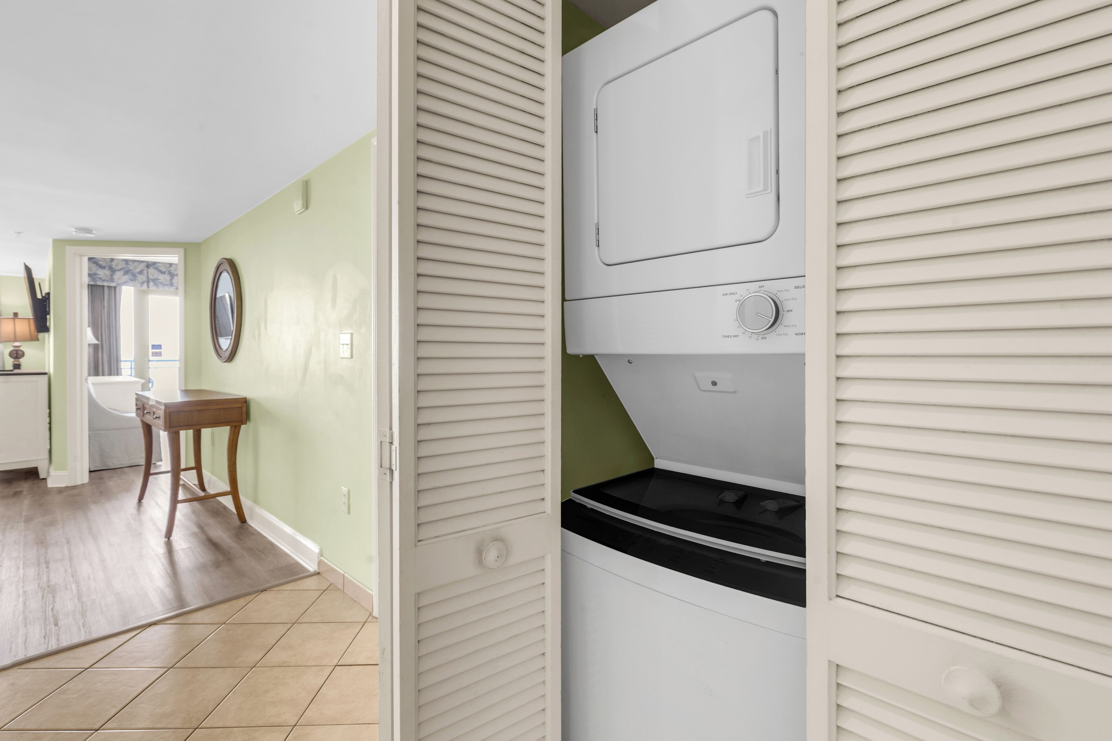 Un cuarto de lavandería con lavadora, secadora y una pequeña mesa con cajones.