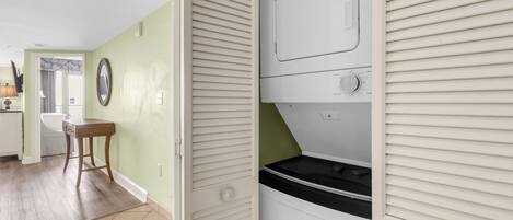 Un cuarto de lavandería con lavadora, secadora y una pequeña mesa con cajones.