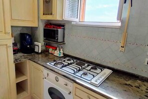 A kitchen with a gas stove, microwave, and various kitchen items on the counter.
