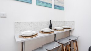 A modern kitchen with a marble countertop, a wine bottle, and three plates.