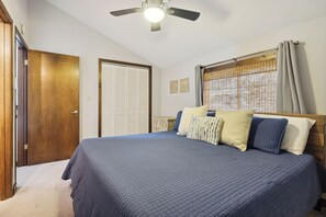 A bedroom with a bed, a ceiling fan, a window with curtains, and a door. - Ober Gatlinburg | Private Hot Tub | Arcade | Free High-Speed Wi-Fi (Gatlinburg)