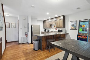 A modern kitchen with a central island, wooden cabinets, and a retro gaming console. - Ober Gatlinburg | Private Hot Tub | Arcade | Free High-Speed Wi-Fi (Gatlinburg)