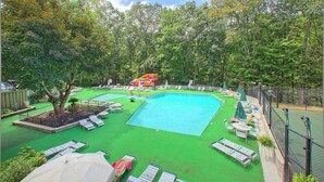 A swimming pool with multiple lanes, surrounded by green artificial turf and shaded by umbrellas. - Ober Gatlinburg | Private Hot Tub | Arcade | Free High-Speed Wi-Fi (Gatlinburg)