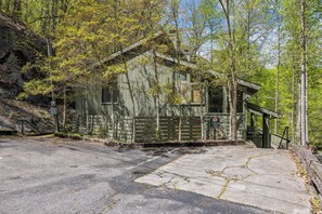 A rustic cabin with a wooden exterior, a small porch, and a 'No Parking' sign indicating a loading zone.