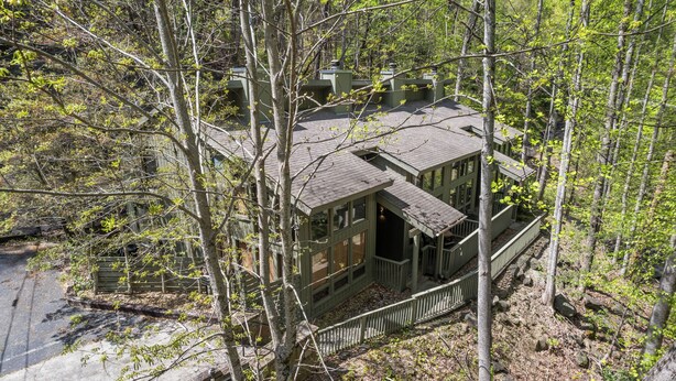 A cabin surrounded by trees with a porch and a small deck. - Ober Gatlinburg | Private Hot Tub | Arcade | Free High-Speed Wi-Fi (Gatlinburg)