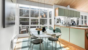 A modern kitchen with a dining area, large windows, and a wooden ceiling. - Beautiful home in Hasle with sauna (Hasle)