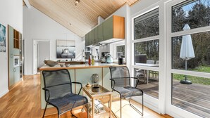 A modern kitchen with a wooden ceiling, large windows, and a dining area with two chairs. - Beautiful home in Hasle with sauna (Hasle)