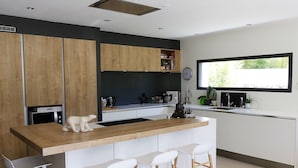 A modern kitchen with a wooden island, white bar stools, and a window with a view of greenery. - Bright and Warm House, quiet, 5min from the center of Aix, (Aix-en-Provence)