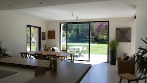 A spacious dining area with a large table, chairs, and a view of a garden through glass doors. - Bright and Warm House, quiet, 5min from the center of Aix, (Aix-en-Provence)