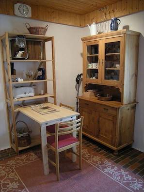 Une cuisine en bois avec une table à manger, des chaises, un buffet et une horloge au mur.